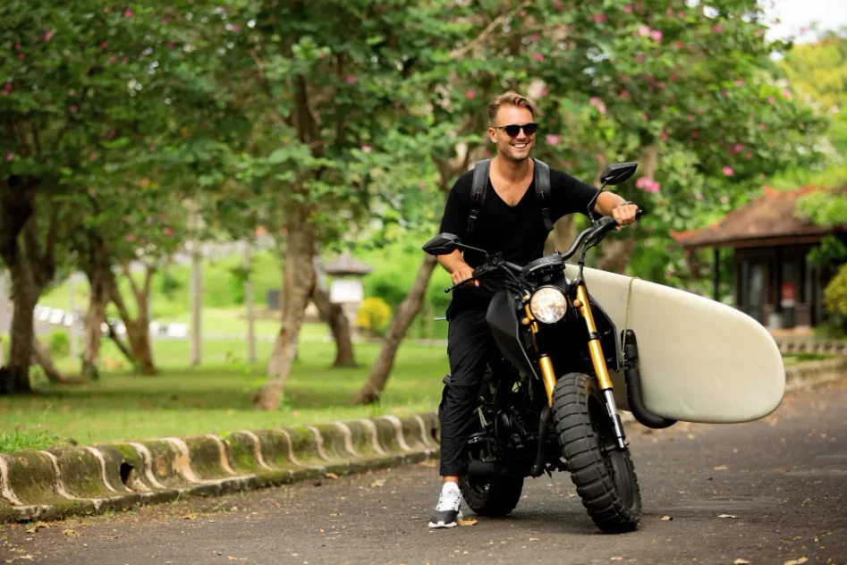 Mand på motorcykel med surfbræt en sommerdag